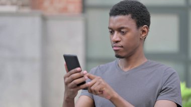 Akıllı telefon kullanan Pozitif Genç Afrikalı Adam Portresi 