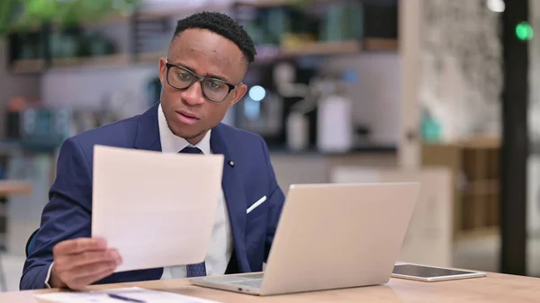 Seriöser Geschäftsmann arbeitet an Laptop mit Dokumenten im Büro — Stockfoto