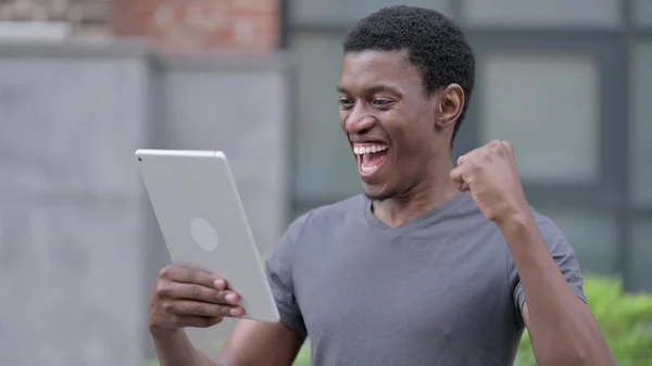 Retrato del excitado diseño africano masculino celebrando el éxito en la tableta —  Fotos de Stock