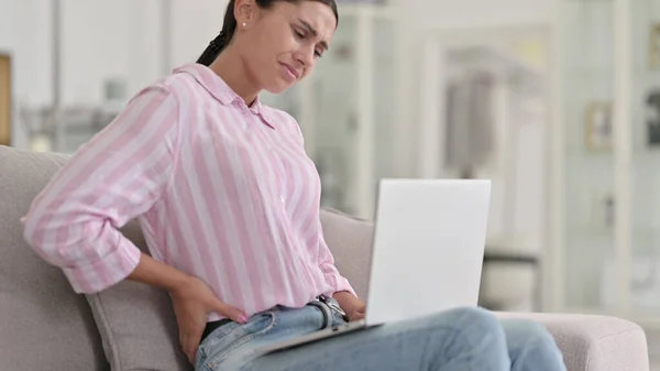 Zmęczona młoda Latynoska z laptopem z bólem pleców w domu — Zdjęcie stockowe