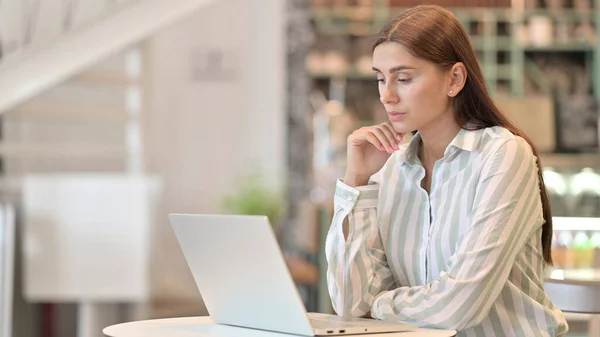 Kafe 'de laptopta düşünen ve çalışan genç Latin kadın. — Stok fotoğraf