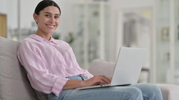 Młoda Latynoska z laptopem uśmiechnięta do kamery w domu — Zdjęcie stockowe