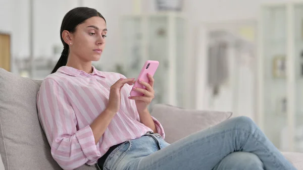 Jeune femme latine détendue utilisant un smartphone à la maison — Photo