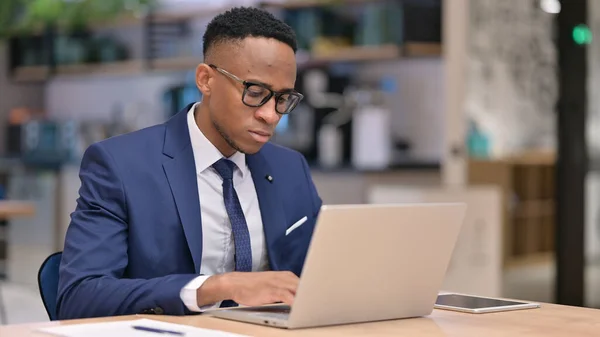 Fokuserad ung afrikansk affärsman som arbetar på laptop i Office — Stockfoto