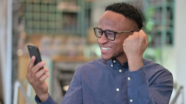 Retrato do homem africano comemorando o sucesso no smartphone — Fotografia de Stock