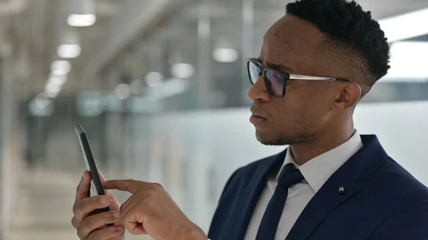Porträt eines attraktiven afrikanischen Geschäftsmannes mit Smartphone — Stockfoto