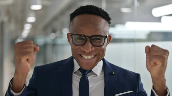 Porträt eines aufgeregten jungen afrikanischen Geschäftsmannes, der Erfolg feiert — Stockfoto