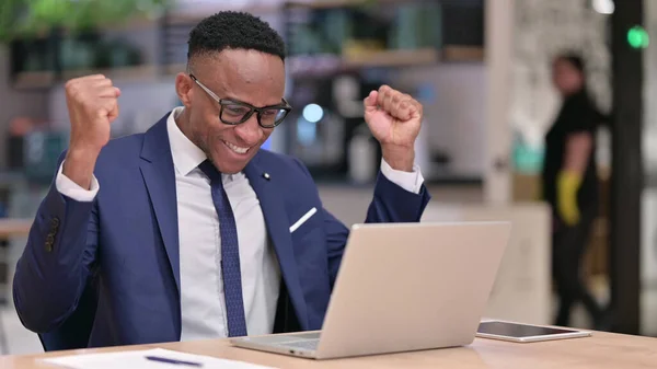 Jeune homme d'affaires africain excité célébrant le succès sur ordinateur portable au bureau — Photo