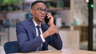 Neşeli genç Afrikalı İş Adamı Ofiste Telefonda konuşuyor