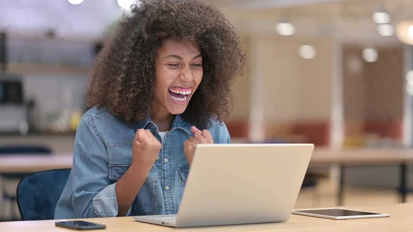Aufgeregte Afrikanerin feiert Erfolg am Laptop bei der Arbeit — Stockfoto
