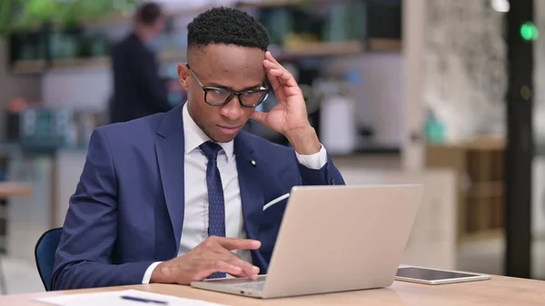 Umsichtiger junger afrikanischer Geschäftsmann denkt und arbeitet im Büro am Laptop — Stockfoto