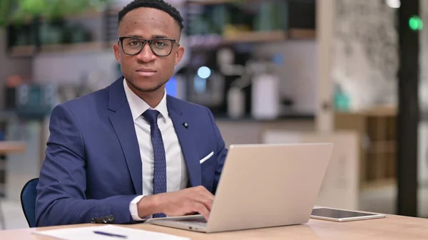 Seriös ung afrikansk affärsman med laptop Tittar på kameran — Stockfoto