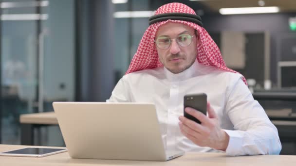 Araber mittleren Alters mit Laptop und Smartphone im Büro — Stockvideo