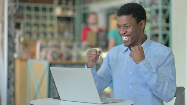 Spännande afrikansk man firar framgång på laptop i Cafe — Stockfoto