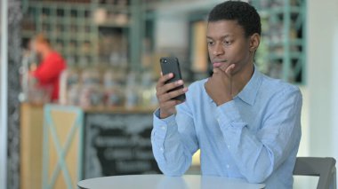 Dalgın Genç Afrikalı Kafe 'de Akıllı Telefondan Okuyor 