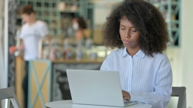 Kafe 'de dizüstü bilgisayarda çalışan odaklanmış genç Afrikalı kadın 