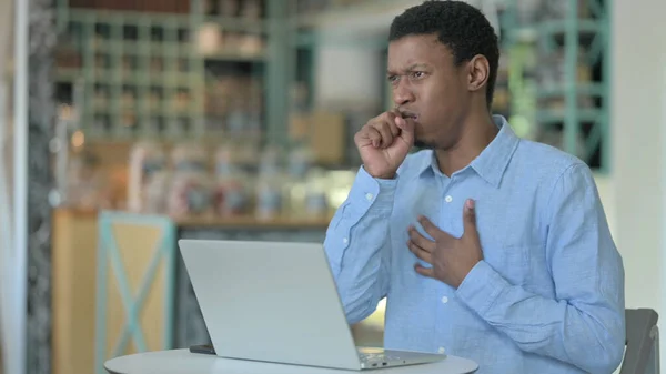 Malade jeune homme africain en utilisant ordinateur portable tousser dans Cafe — Photo