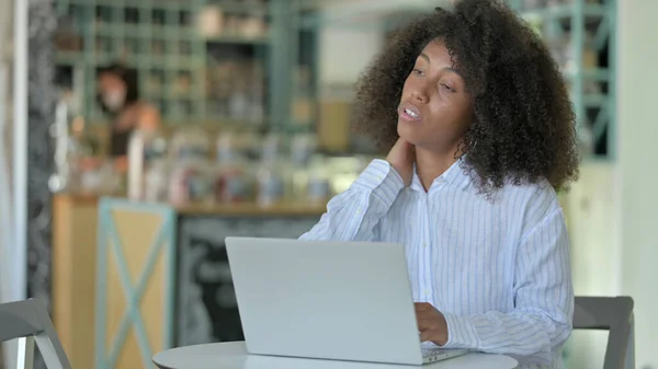 Cansado jovem mulher africana com laptop tendo dor no pescoço no café — Fotografia de Stock