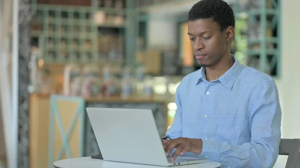 Konzentrierter junger Afrikaner benutzt Laptop im Café — Stockfoto