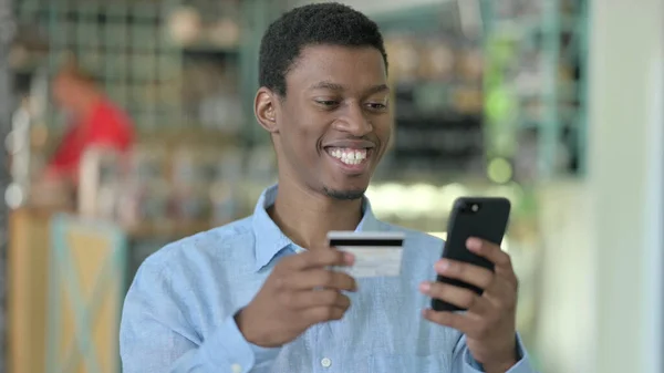 Portrait de jeune homme africain effectuant le paiement en ligne sur Smartphone — Photo