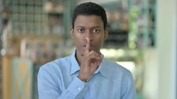 Retrato de un joven africano poniendo dedo en los labios —  Fotos de Stock