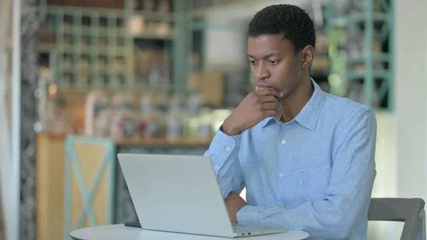 在咖啡店用笔记本电脑的多愁善感的非洲年轻人 — 图库照片