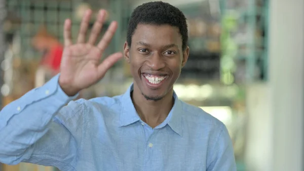 Porträt eines fröhlichen jungen Afrikaners, der winkt, hallo — Stockfoto