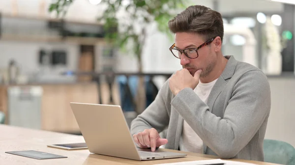 Orta yaşlı adam laptopta düşünüyor ve çalışıyor 