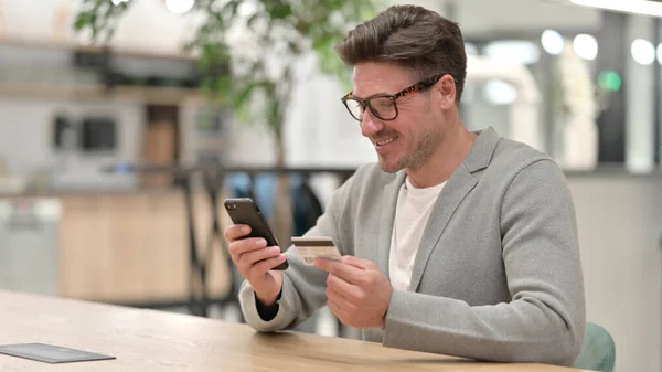 Hombre de mediana edad que hace el pago en línea en Smartphone —  Fotos de Stock