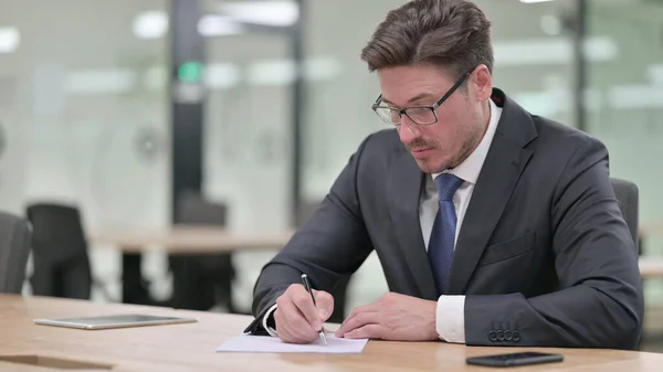 Un homme d'affaires du Moyen Âge concentré écrivant sur le papier au bureau — Photo