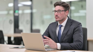 Düşünceli Orta Çağ İşadamı Ofiste Dizüstü bilgisayarla Düşünüyor ve Çalışıyor 