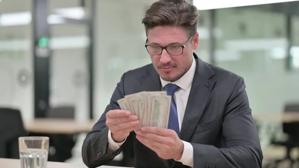 Retrato del empresario de mediana edad satisfecho contando dólares —  Fotos de Stock