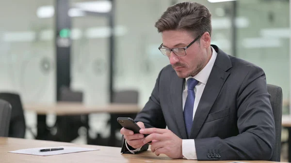 Ελκυστικός μεσήλικας επιχειρηματίας που χρησιμοποιεί Smartphone στο γραφείο — Φωτογραφία Αρχείου