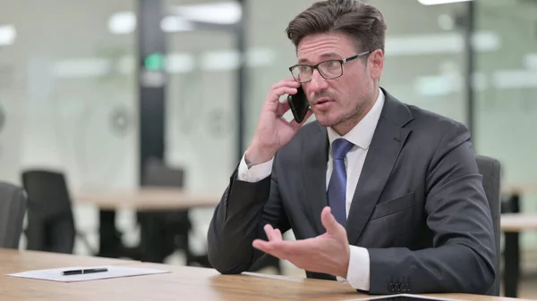 Glada medelålders affärsman talar på telefon i Office — Stockfoto
