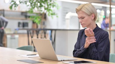 Dizüstü bilgisayarda çalışan stresli kadın ofiste bilek ağrısı çekiyor. 