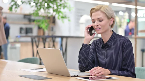 オフィスで電話で話すノートパソコンを持つ若いビジネスマンの女性 — ストック写真