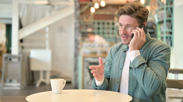 Glada medelålders man talar på telefon i Café — Stockfoto