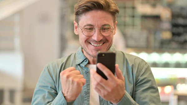 Retrato do homem de meia-idade animado comemorando o sucesso no smartphone — Fotografia de Stock