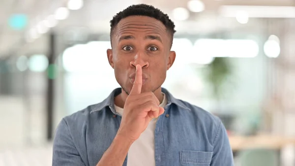 Retrato de homem africano casual colocando o dedo nos lábios, sinal silencioso — Fotografia de Stock
