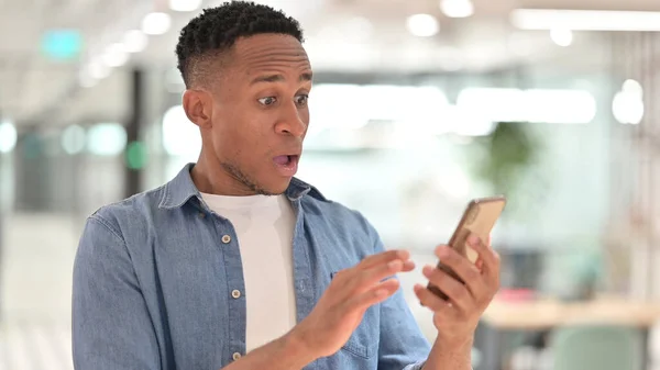 Retrato de homem africano chocado usando smartphone em surpresa — Fotografia de Stock