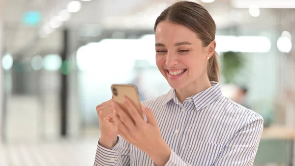 Portrét vzrušené mladé ženy oslavující úspěch na smartphonu — Stock fotografie