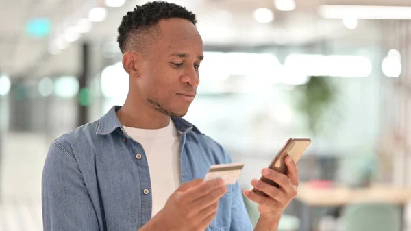 Porträt eines Afrikaners, der mit dem Smartphone online bezahlt — Stockfoto