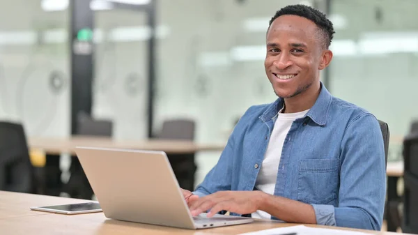 Glada Casual African Man med bärbar dator ler mot kameran — Stockfoto