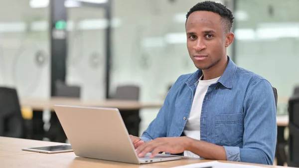 Ernsthafter Afrikaner mit Laptop blickt in die Kamera — Stockfoto