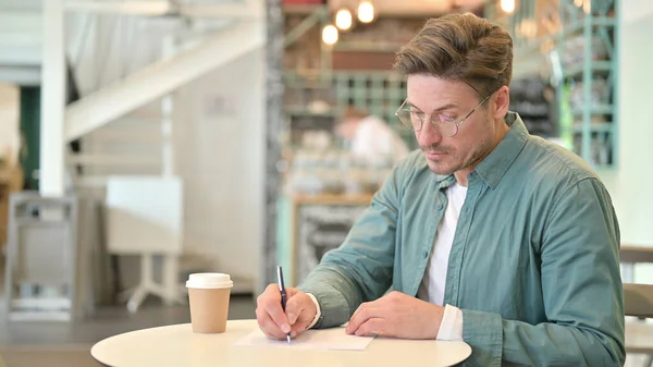 Ernstige Middeleeuwen Man Schrijven op papier in Cafe — Stockfoto