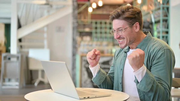 Emocionado hombre de mediana edad celebrando el éxito en el ordenador portátil en Café —  Fotos de Stock