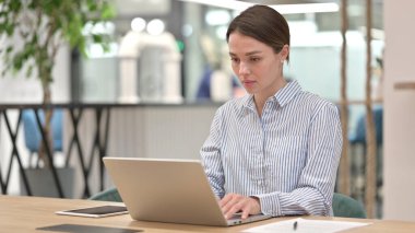 Ofiste dizüstü bilgisayarda çalışan çekici genç kadın. 