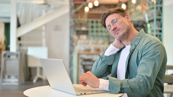 Trött medelålders man med bärbar dator med nacksmärta i Cafe — Stockfoto