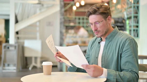 Mann mittleren Alters liest im Café Dokumente — Stockfoto