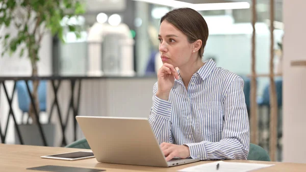 Mujer joven y pensativa sentada en el trabajo —  Fotos de Stock